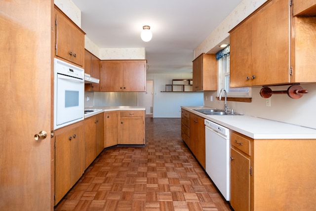 kitchen with sink, white appliances, and light parquet flooring