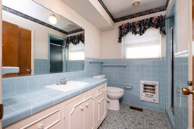 bathroom with tile patterned flooring, tile walls, vanity, heating unit, and toilet