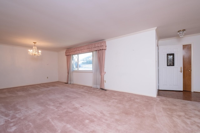 carpeted spare room with ornamental molding and a chandelier