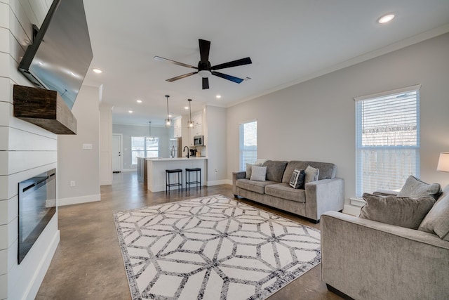 living room featuring crown molding, a fireplace, concrete flooring, and ceiling fan