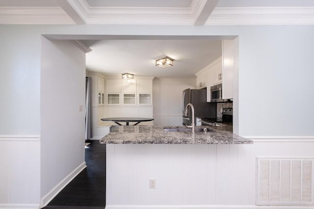 kitchen with stainless steel appliances, white cabinetry, light stone countertops, and kitchen peninsula