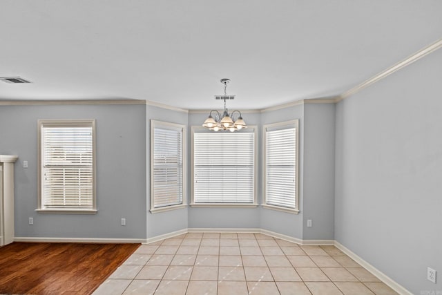 spare room featuring ornamental molding, light tile patterned floors, and an inviting chandelier