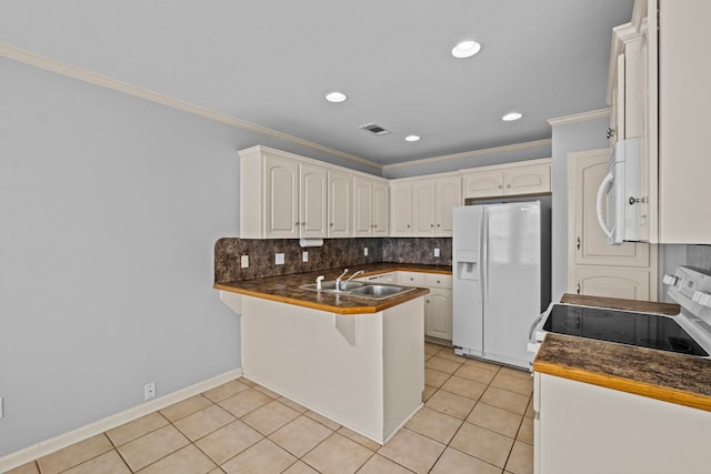 kitchen featuring sink, white appliances, light tile patterned floors, white cabinetry, and kitchen peninsula