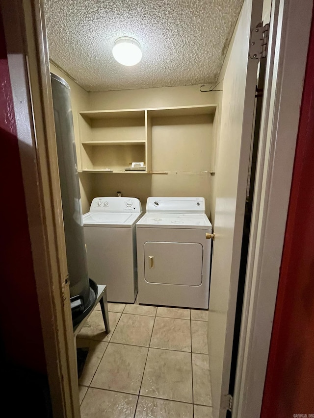 clothes washing area featuring washing machine and dryer, light tile patterned flooring, and a textured ceiling