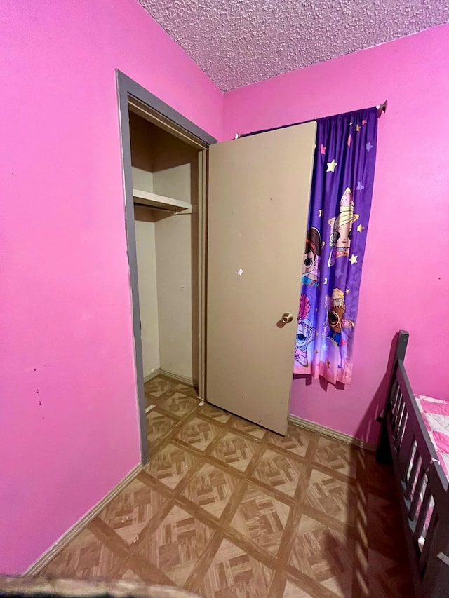 unfurnished bedroom featuring parquet floors and a textured ceiling