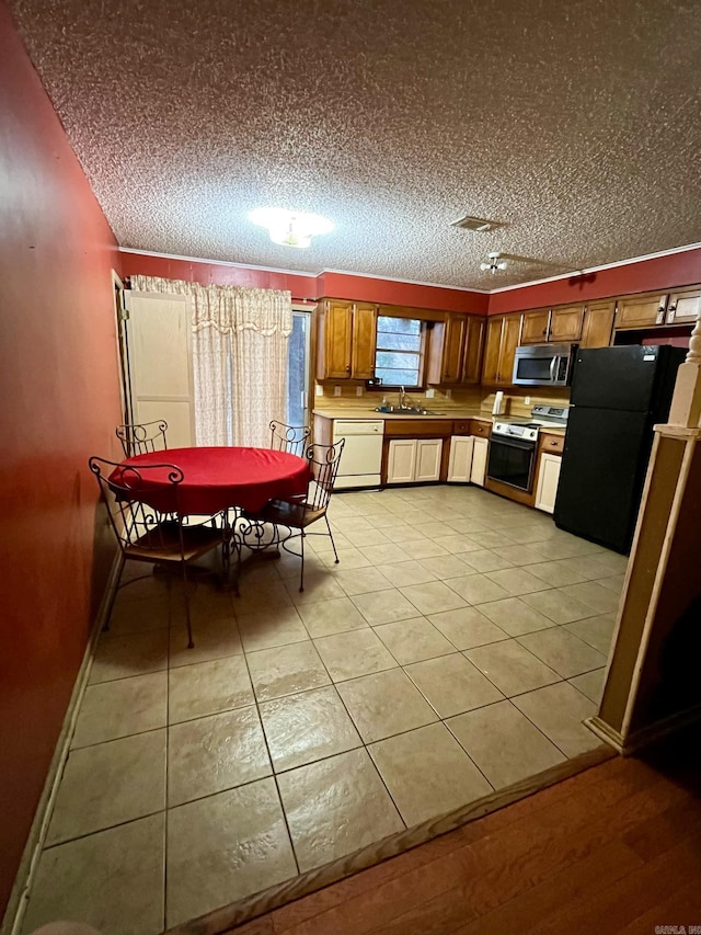 kitchen with stainless steel appliances, sink, a textured ceiling, and light tile patterned floors