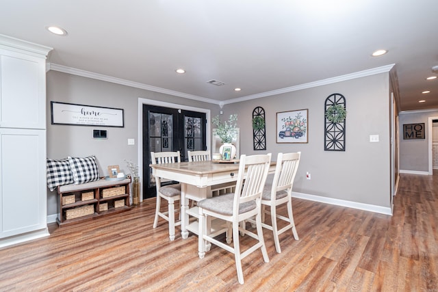 dining room featuring french doors, crown molding, and light wood-type flooring