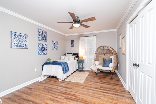 bedroom with crown molding, ceiling fan, wood-type flooring, and a closet