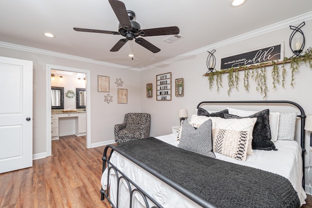 bedroom featuring built in desk, connected bathroom, wood-type flooring, ornamental molding, and ceiling fan