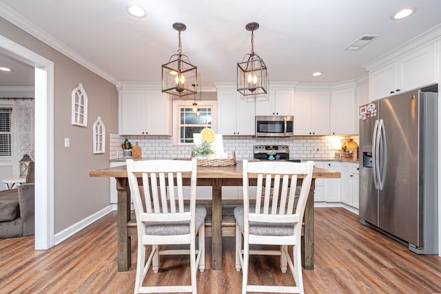 kitchen featuring pendant lighting, stainless steel appliances, a center island, white cabinets, and decorative backsplash