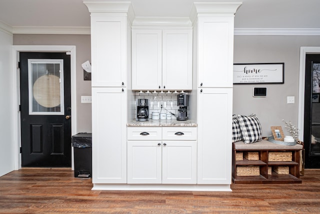 interior space with light stone counters, crown molding, and white cabinets