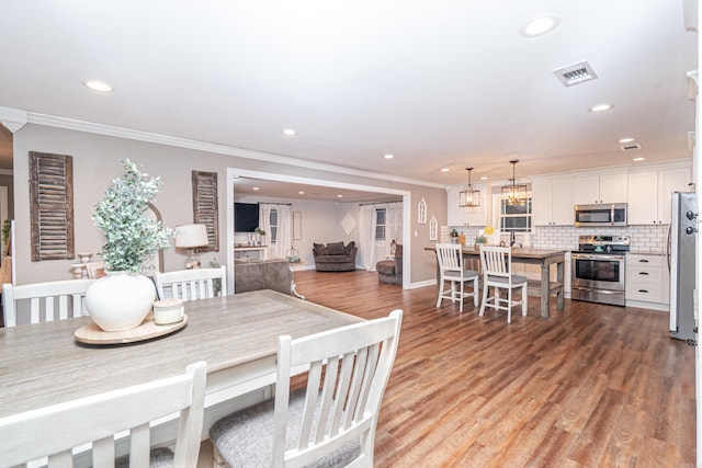 dining area featuring ornamental molding, a notable chandelier, and light wood-type flooring