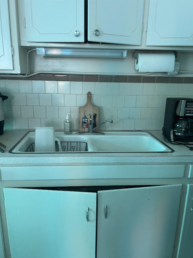 kitchen with white cabinetry, backsplash, and electric panel