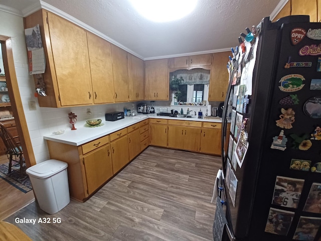 kitchen with black refrigerator, tasteful backsplash, sink, light hardwood / wood-style floors, and crown molding