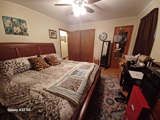 bedroom with hardwood / wood-style floors, ornamental molding, a closet, and ceiling fan