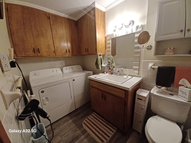 bathroom with washing machine and clothes dryer, toilet, sink, wood-type flooring, and ornamental molding