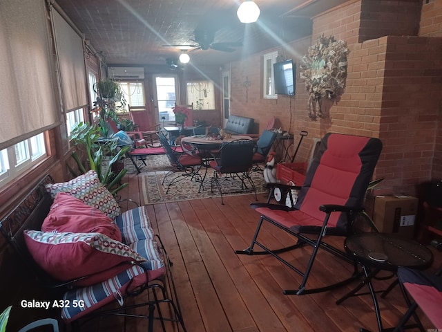 interior space with hardwood / wood-style flooring, brick wall, and a wall unit AC