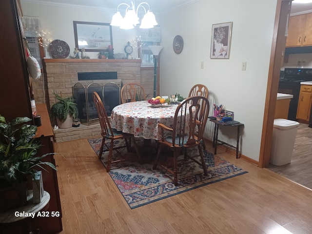 dining room with an inviting chandelier, a fireplace, ornamental molding, and light hardwood / wood-style floors