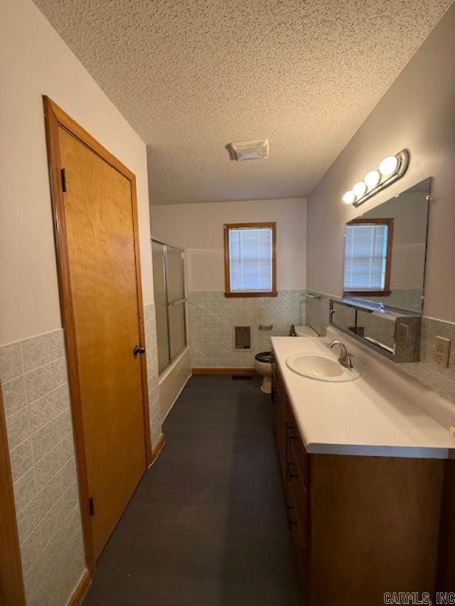 full bathroom featuring vanity, tile walls, a textured ceiling, and toilet