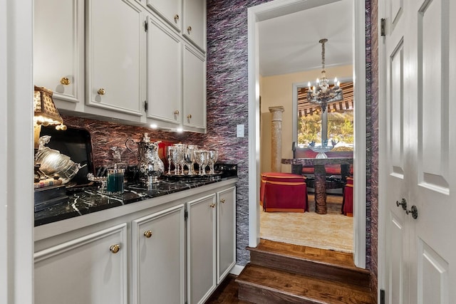 kitchen featuring backsplash, a notable chandelier, decorative light fixtures, and white cabinets