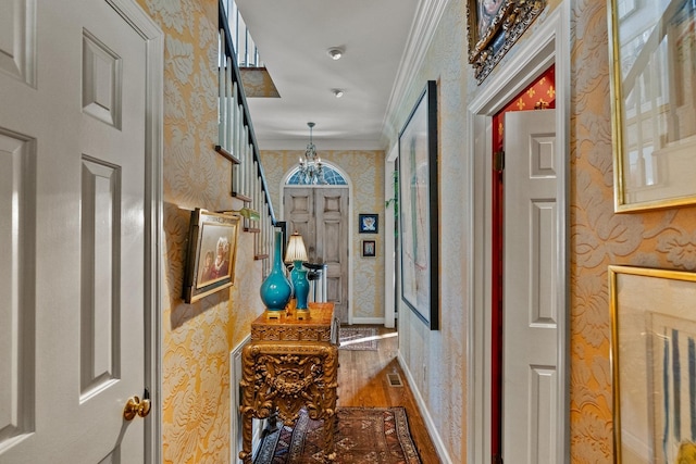 corridor with hardwood / wood-style floors, crown molding, and a chandelier