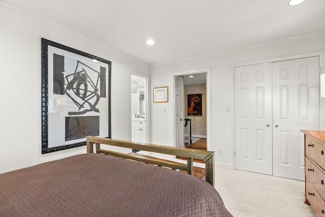 bedroom featuring ornamental molding, light carpet, ensuite bath, and a closet