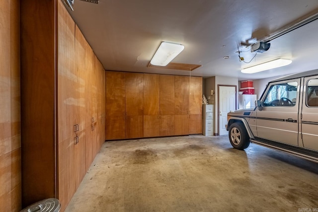 garage featuring a garage door opener, refrigerator, and wooden walls