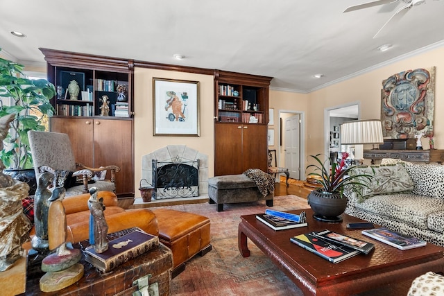 living room featuring a tiled fireplace, ornamental molding, and ceiling fan