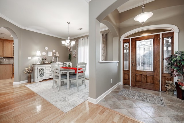 foyer with crown molding, plenty of natural light, light hardwood / wood-style floors, and a chandelier