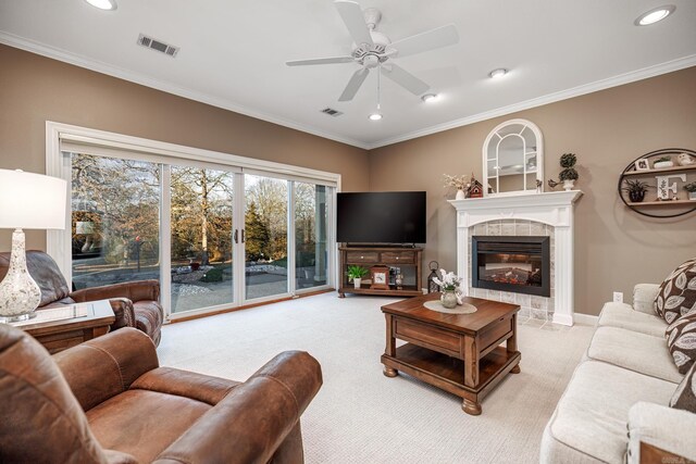 living room featuring crown molding, light colored carpet, a fireplace, and ceiling fan