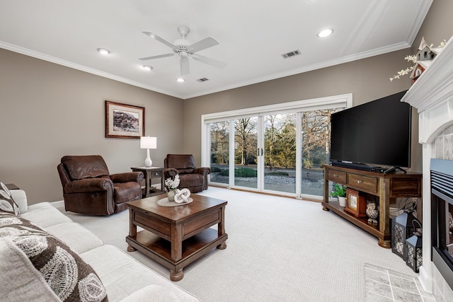 living room with ceiling fan, light colored carpet, ornamental molding, and a tiled fireplace