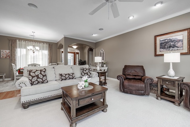 living room with ornamental molding, ceiling fan with notable chandelier, and light carpet