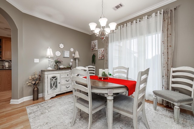 dining room featuring ornamental molding, sink, a notable chandelier, and light hardwood / wood-style floors