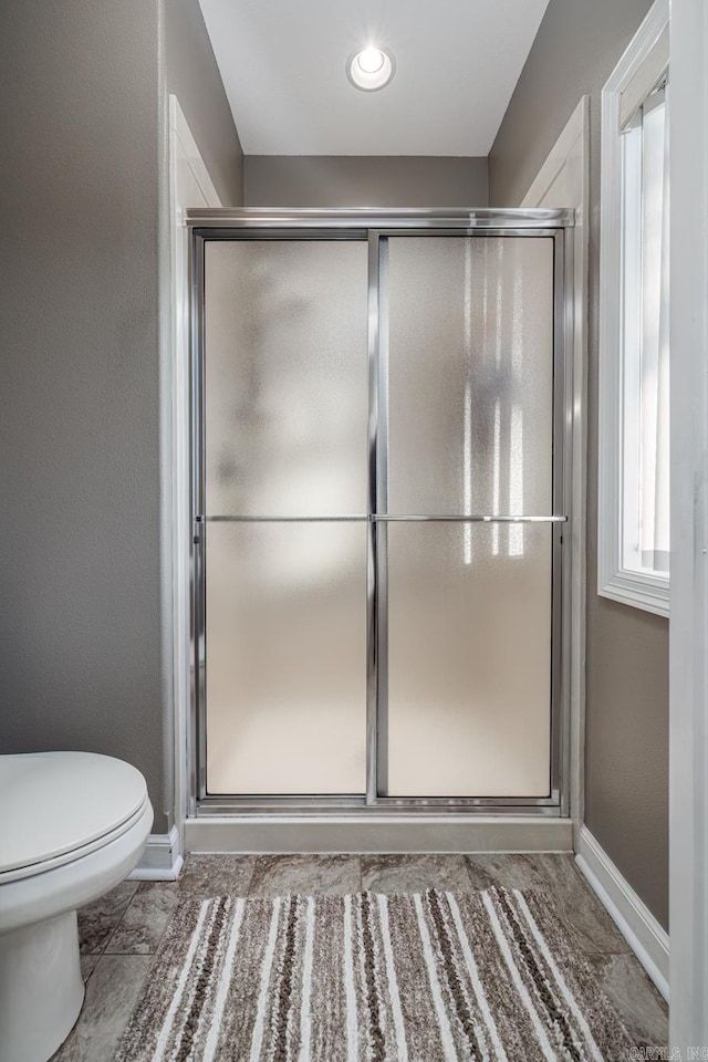 bathroom with a shower with door and toilet