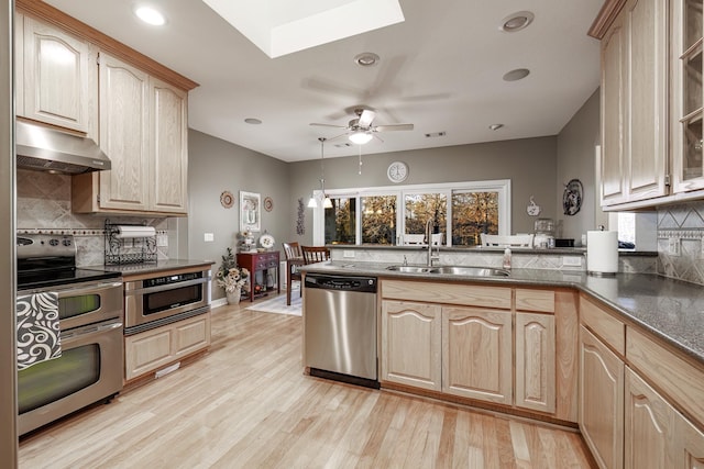 kitchen featuring tasteful backsplash, a skylight, stainless steel appliances, and light brown cabinets