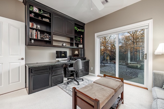 carpeted office with built in desk and ceiling fan