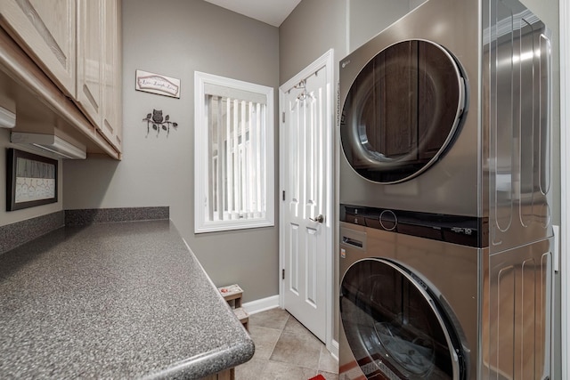 washroom featuring cabinets, stacked washing maching and dryer, and light tile patterned floors