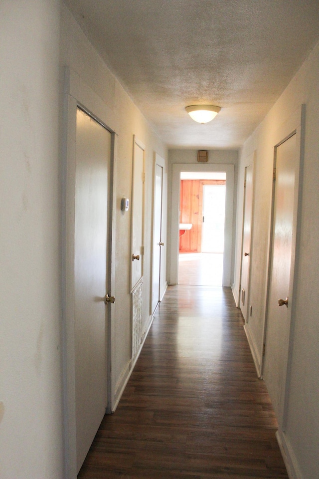 corridor featuring dark hardwood / wood-style floors and a textured ceiling