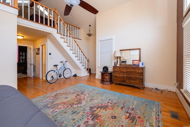 bedroom featuring wood-type flooring, a towering ceiling, and ceiling fan