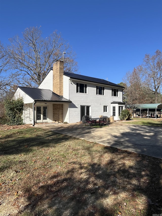 back of property featuring french doors, a patio, and a lawn