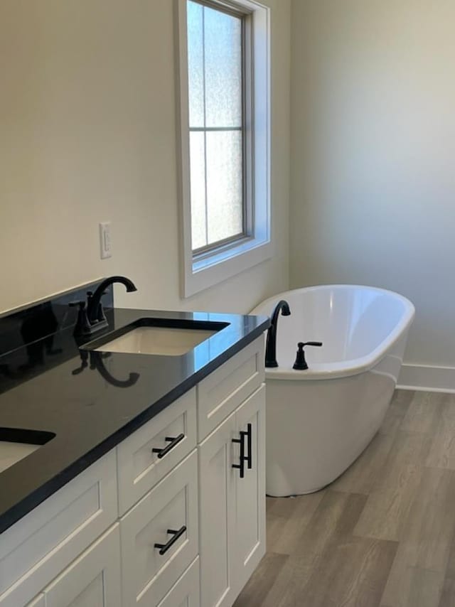 bathroom with a tub to relax in, vanity, and hardwood / wood-style floors