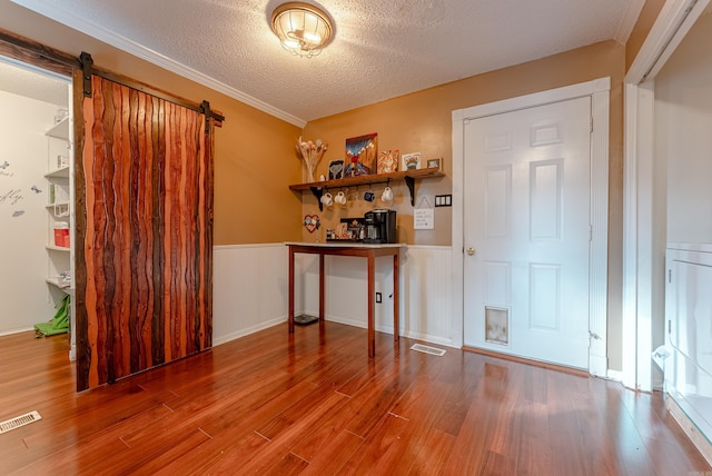 interior space with hardwood / wood-style flooring, a barn door, and a textured ceiling