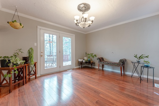 doorway to outside with ornamental molding, wood-type flooring, and a chandelier