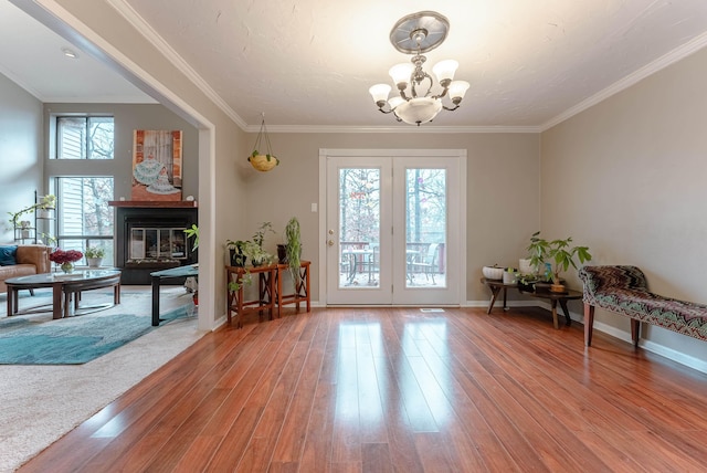 living area with hardwood / wood-style flooring, crown molding, and a notable chandelier