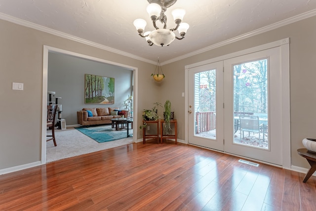 doorway featuring an inviting chandelier, ornamental molding, and hardwood / wood-style flooring