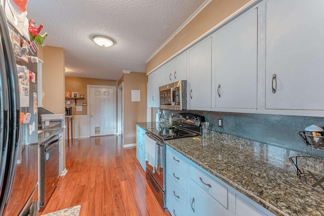 kitchen with appliances with stainless steel finishes, white cabinetry, tasteful backsplash, light hardwood / wood-style floors, and a textured ceiling