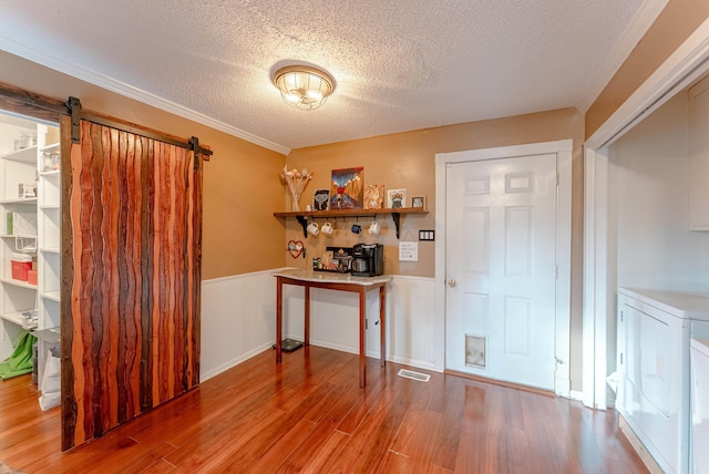 interior space featuring hardwood / wood-style flooring, a barn door, a textured ceiling, and independent washer and dryer