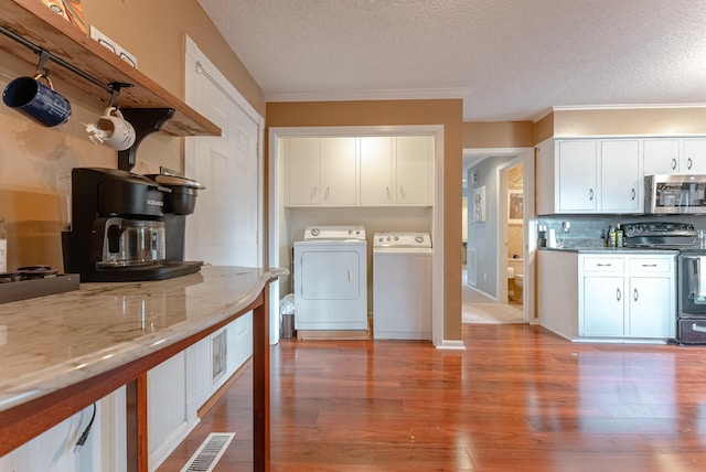 kitchen with electric stove, white cabinets, light stone countertops, and washing machine and clothes dryer