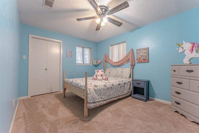 carpeted bedroom featuring a textured ceiling, ceiling fan, and a closet