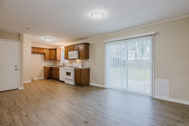 kitchen featuring sink, backsplash, light stone counters, light hardwood / wood-style floors, and white appliances